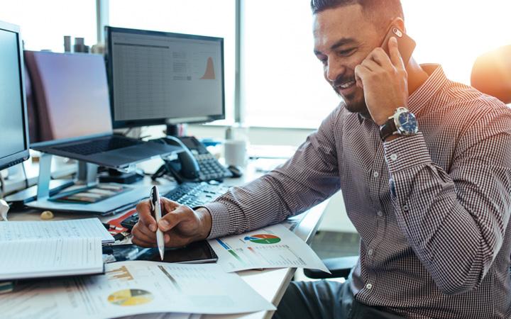 Man working at desk while speaking on the phone.