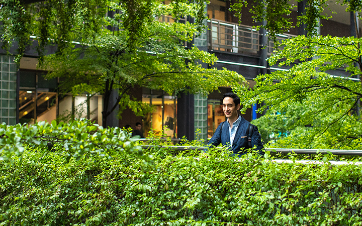 Man walking through a leafy, green area, symbolizing sustainable travel options